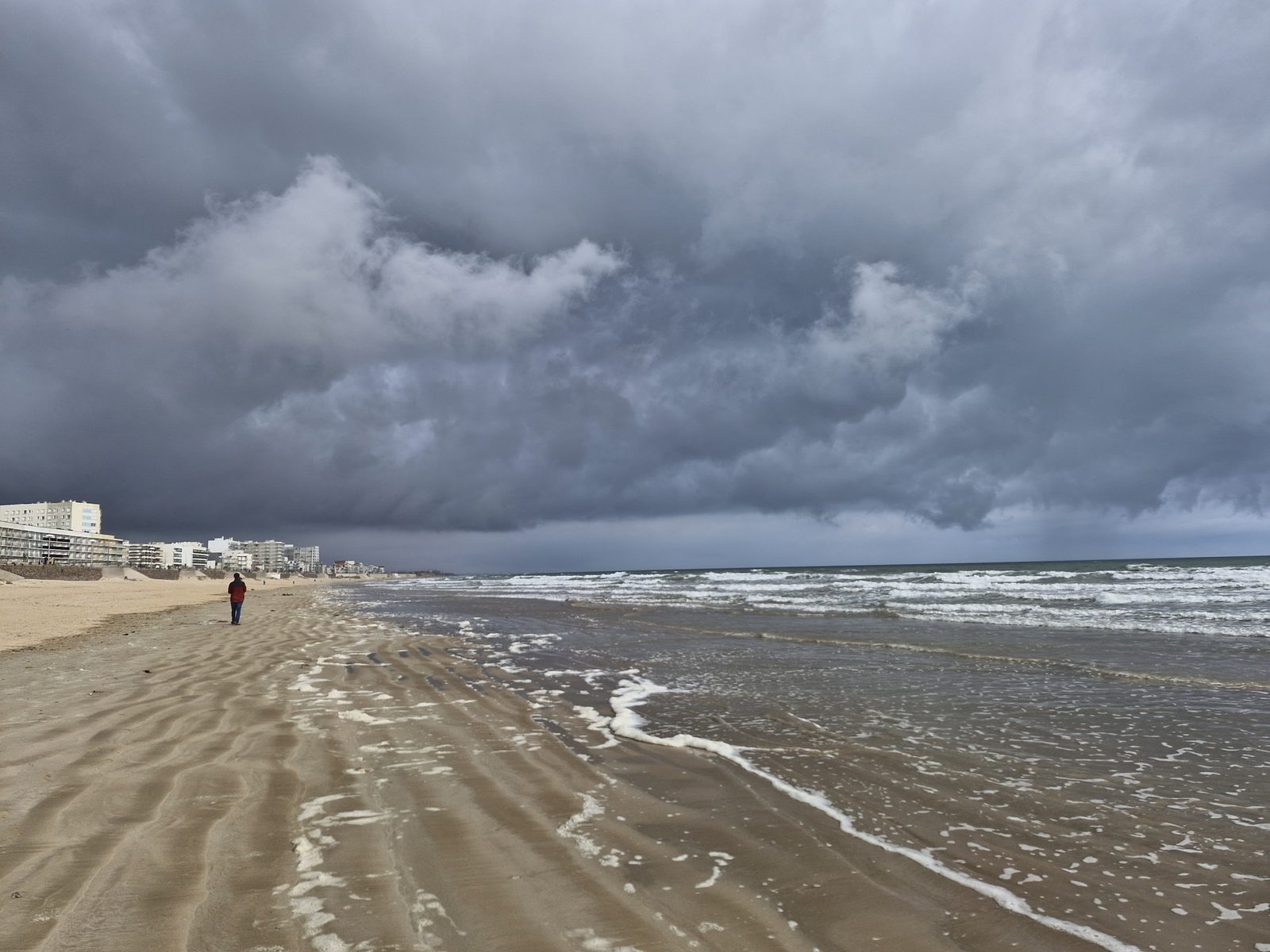 Ciel d’orage au-dessus de la grande plage, un promeneur au loin