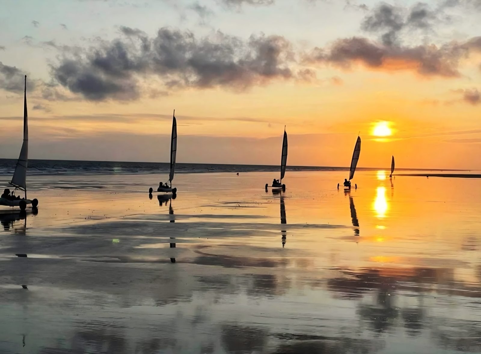 Chars à voile sur l’estran mouillé au soleil couchant