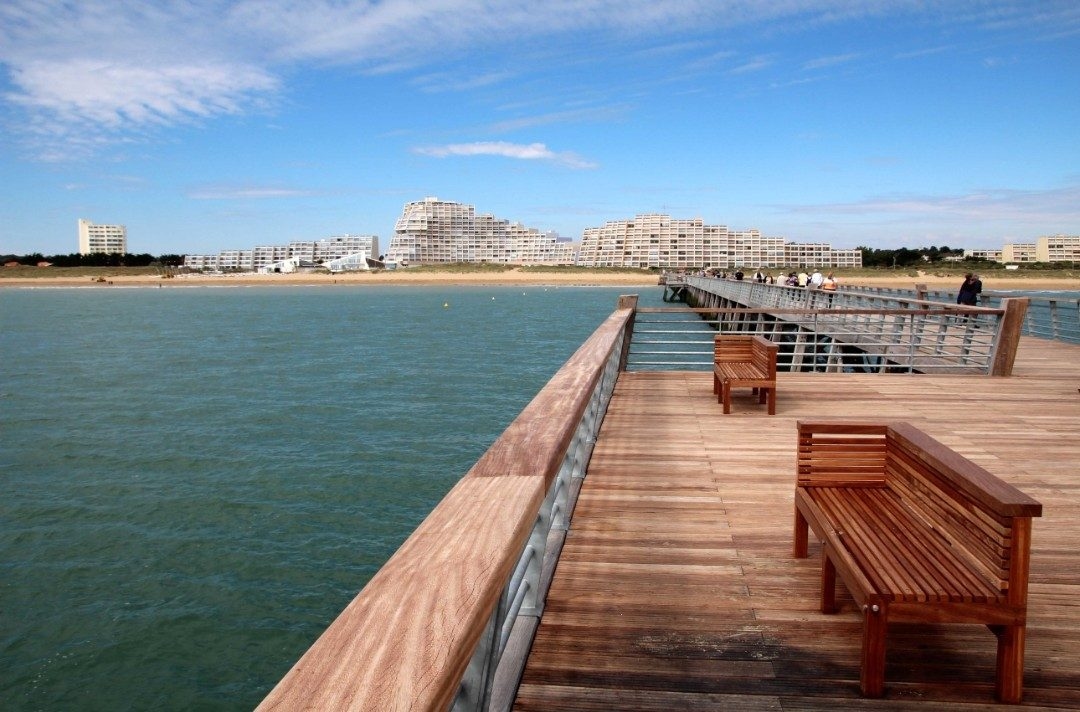 Le platelage de bois de l’estacade et ses bancs, au-dessus de la mer