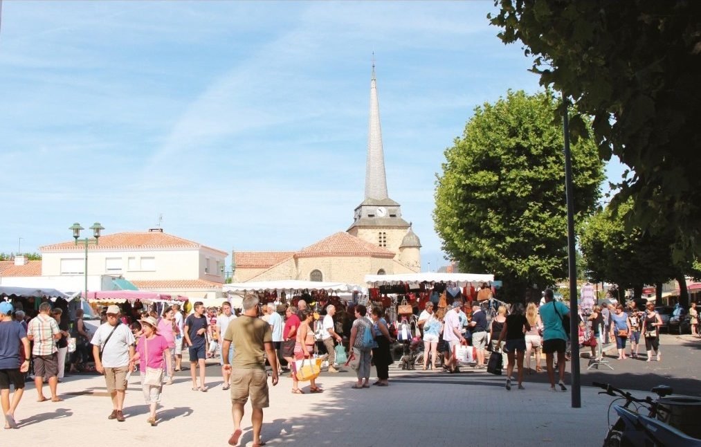 La foule entre les étals du marché, au pied du clocher