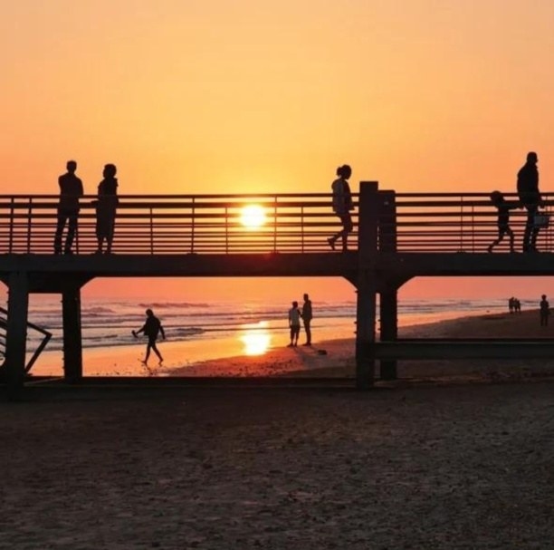 Promeneurs en silhouette sur l’estacade au soleil couchant